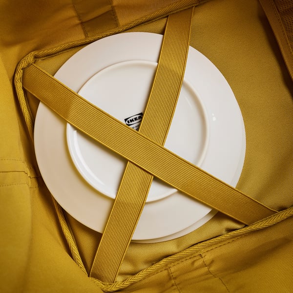 White plate in green mesh bag. Straps crisscross, securing plate. Bag appears durable, well-constructed.