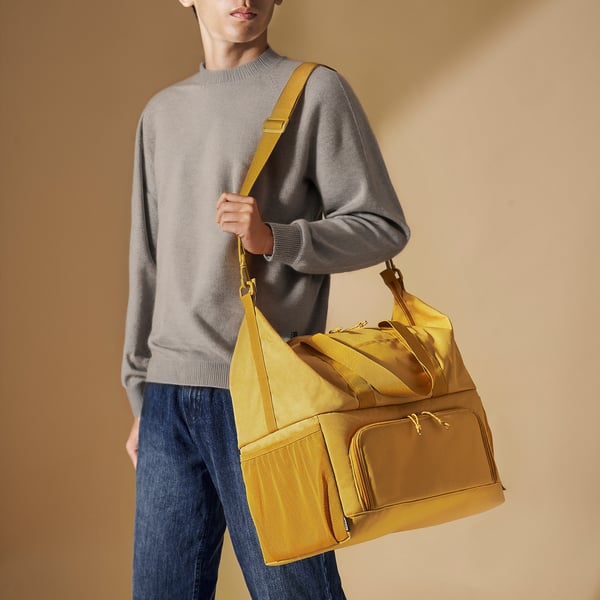Person holding yellow picnic/shopping cooler with mesh pockets.