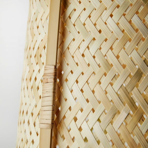 Woven bamboo lamp, intricately handcrafted, provides soft glowing light.