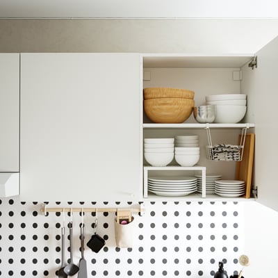 Kitchen cabinet with stacked bowls, plates, and utensils.