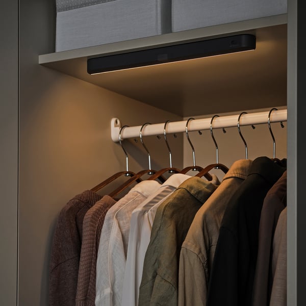 Closet with KÖLVATTEN led light, illuminating clothes on hangers and shelf.