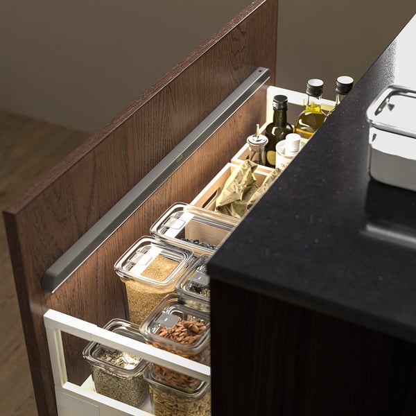 Kitchen drawer with pull-out organiser: clear containers store grains, nuts, and seasonings; oil bottles on top.