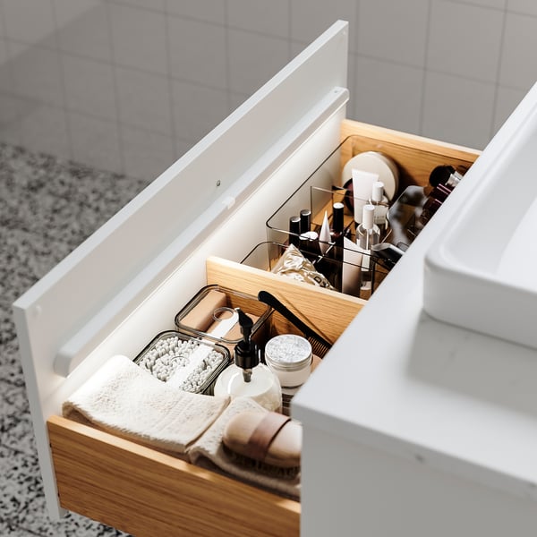 Open bathroom drawer revealing neatly organised toiletries, with automatically lit KÖLVATTEN light inside.