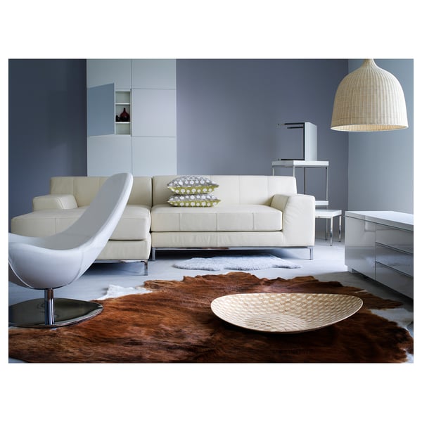 Modern living room with white sofa, hide rug, bull-shaped floor lamp, and woven pendant light.