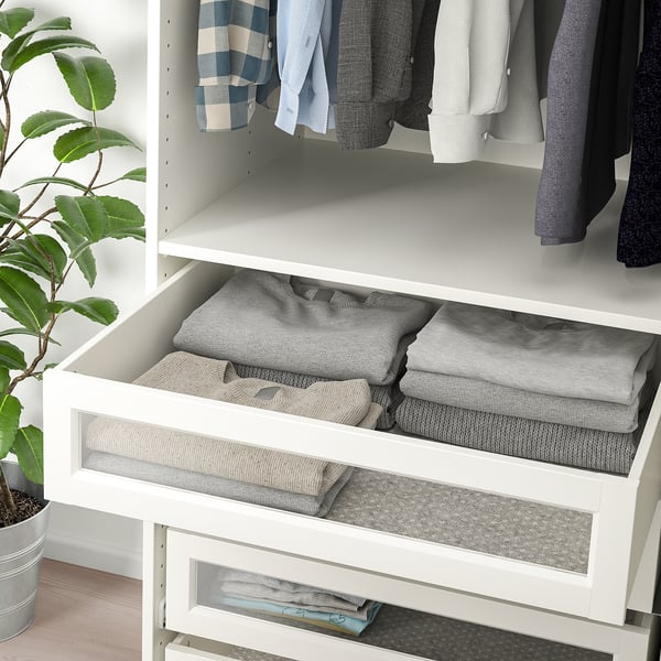 A white system wardrobe with clear glass drawers neatly folded grey clothes.