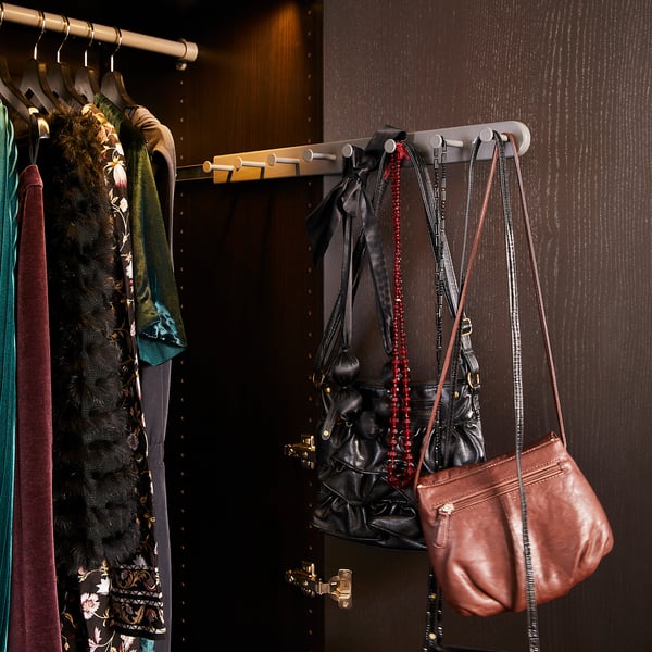 Closet with colourful clothes and accessories. Purses hang to the right, including a brown leather bag.