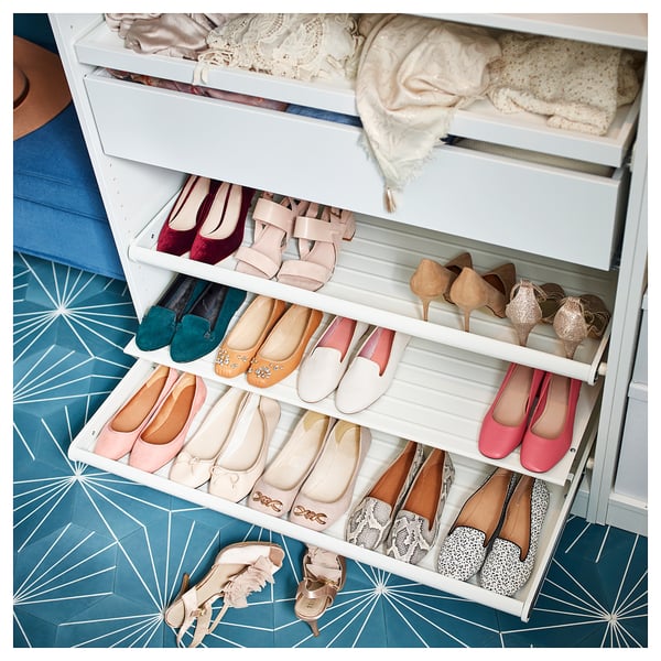 White shoe rack with 6 shelves, holding womens heels, flats, sandals in a blue geometric-patterned closet.