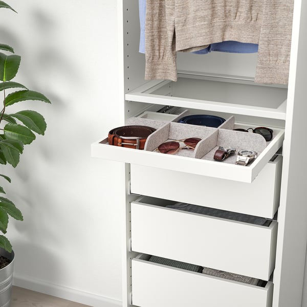 White drawer organiser holding belts and sunglasses, part of IKEAs KOMPLEMENT series, designed for storing accessories neatly.