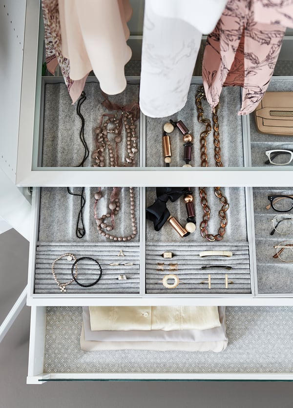 Organised jewellery tray: white KOMPLEMENT drawer with felt inserts, holding necklaces, rings, and watches.