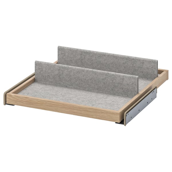An IKEA KOMPLEMENT pull-out tray organiser with grey felt lining, wooden frame, and metallic accents.