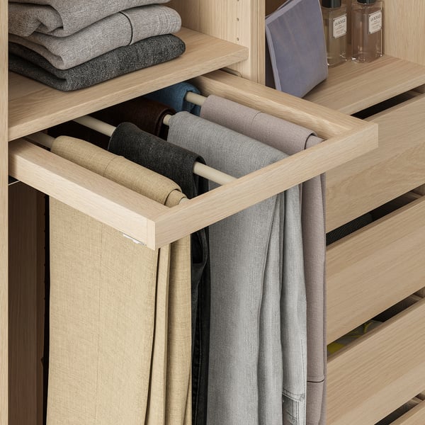 Open wooden wardrobe with trouser hanger, holding multiple pairs of neatly rolled pants.