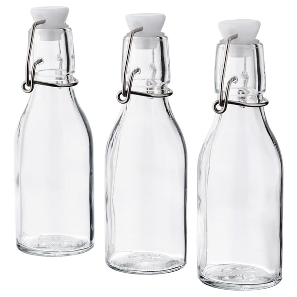 Three clear KORKEN glass bottles with white stoppers and metal clamps, arranged side by side.
