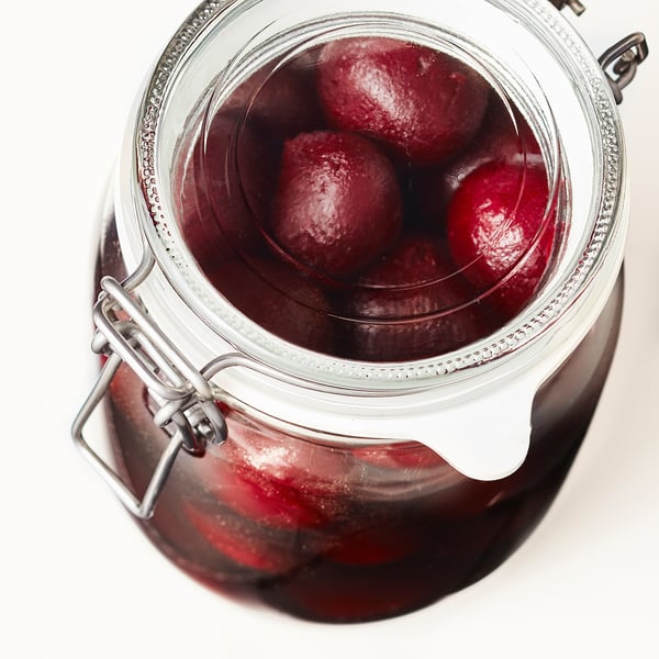 Clear glass jar with metal clamps holds red-purple pickled beets. Airtight seal preserves flavours and aromas.