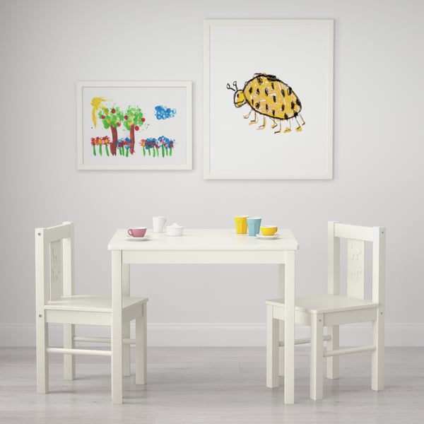 Kids play area with white table and chairs, colourful cups, and bug-themed art.
