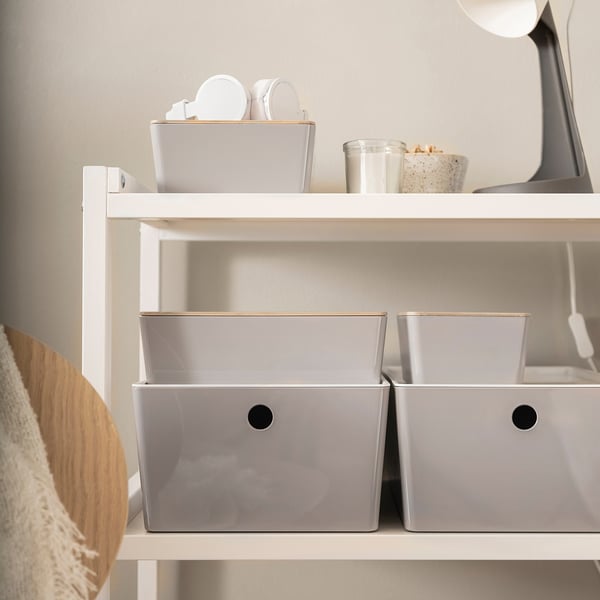White shelves with three grey KUGGIS boxes, organising small items. Boxes fit neatly into shelves.