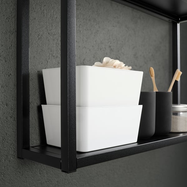 Black shelf with stacked white KUGGIS boxes holding bathroom items.