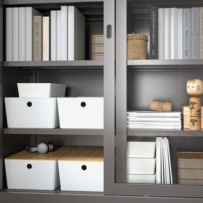 Organised shelves with KUGGIS boxes, holding various items like books and small accessories. Boxes have bamboo lids for dust protection.