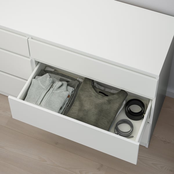 Open white chest drawer revealing neatly folded clothes and kitchen items.