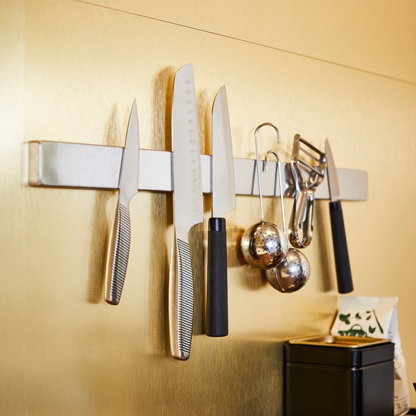 Magnetic knife rack on wall, storing multiple knives and utensils safely.