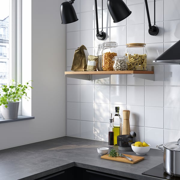 Modern kitchen with KUNGSFORS shelf, jars, and bags. Dark counters, herbs, lemons, and black lamps.