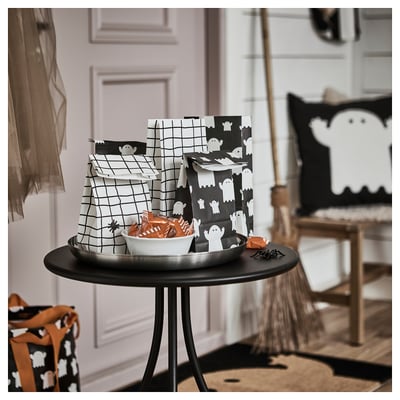 Halloween table setup with KUSTFYR bags, candy, pillow, chair.