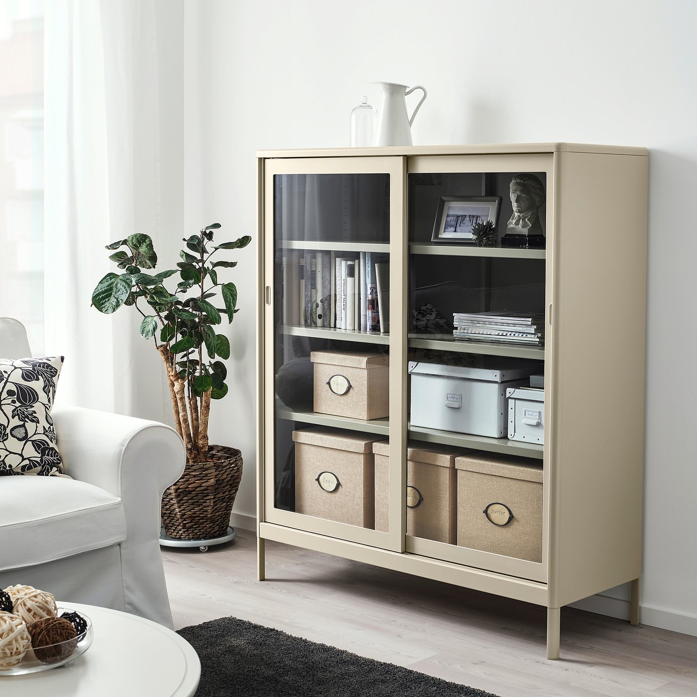 Modern beige KVARNVIK storage in living room with glass doors, showing books and decor.