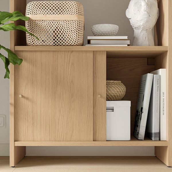 Light wooden LÅDMAKARE cabinet with woven baskets and books on top, featuring closed storage.