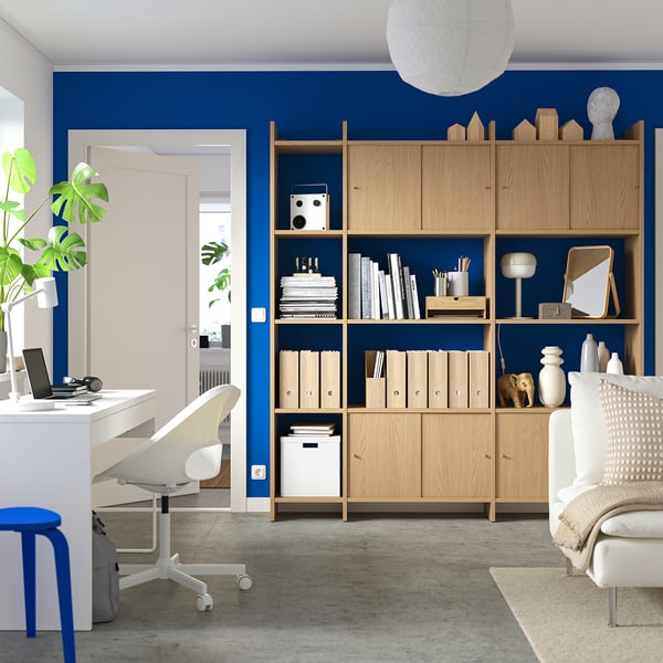 Modern home office with LÅDMAKARE storage: light wood, blue wall, books, laptop.