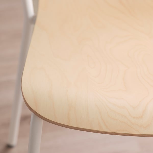 Close-up of a sturdy, light birch veneer tabletop with visible wood grain, supported by white metal legs.