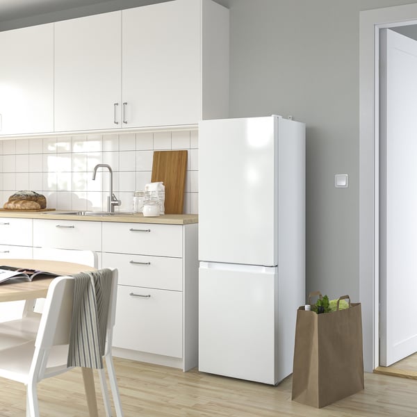 Modern white LAGAN fridge in kitchen, tall with led light, next to cabinets and chairs.
