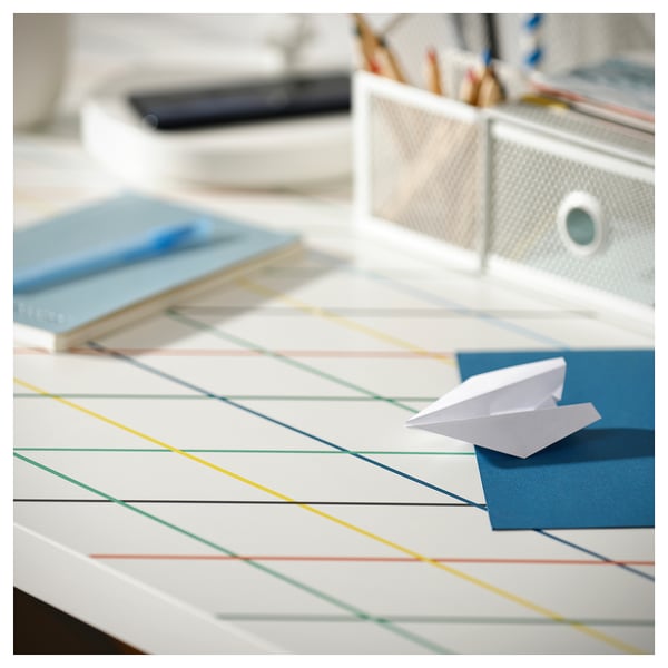A colourful desk with a grid pattern and a paper aeroplane on it.