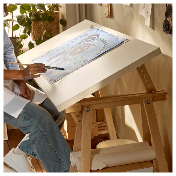 Person drawing on a white LAGKAPTEN table with lightwood trestle legs.
