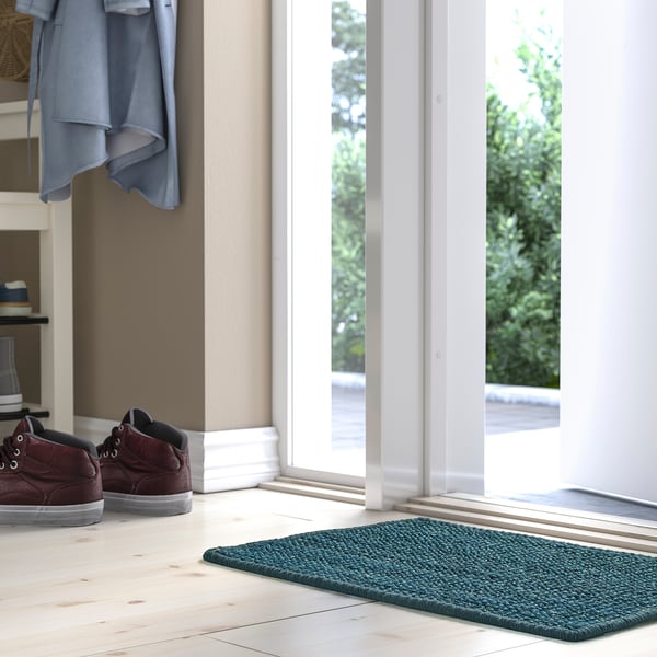 Entryway scene with blue LANDBANA mat, wood floor, and glass door.