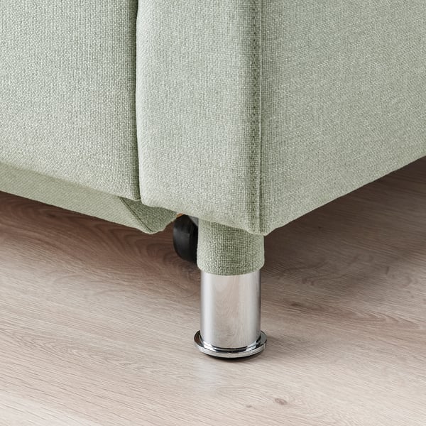 Modern chrome legs support green upholstered sofa, showcasing sturdy design.
