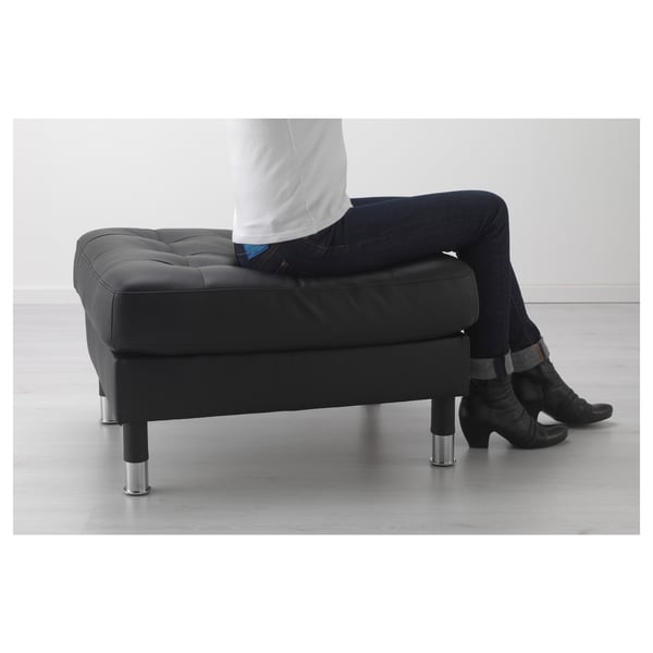 Person sitting on black LANDSKRONA ottoman with chrome legs.