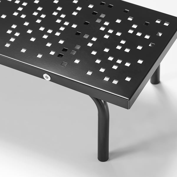Black metal desk with perforated pattern, round legs, and smooth edges; sturdy and stylish.