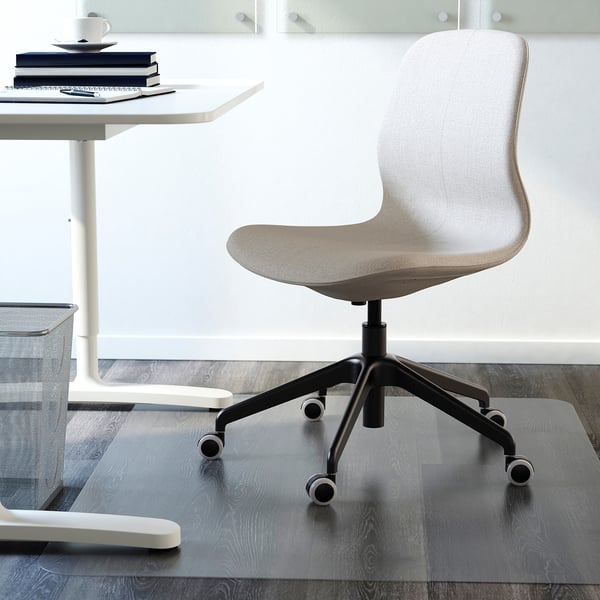 Grey office chair with wheels at white desk, books, and cup.