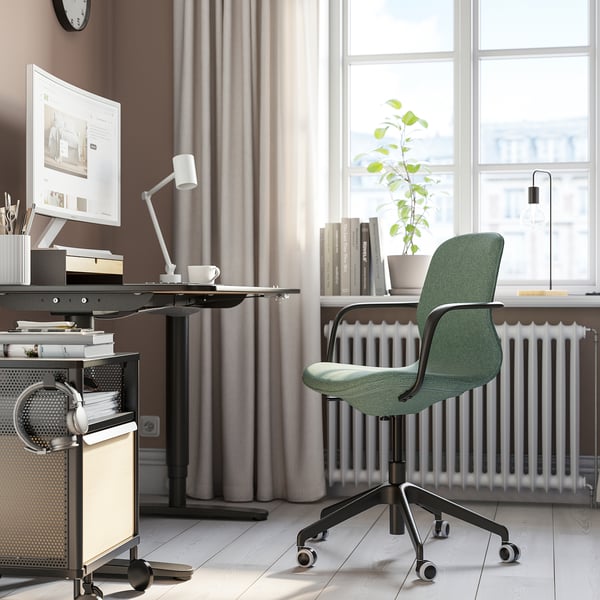 Green LÅNGFJÄLL office chair in workspace with adjustable positioned near desk and window.