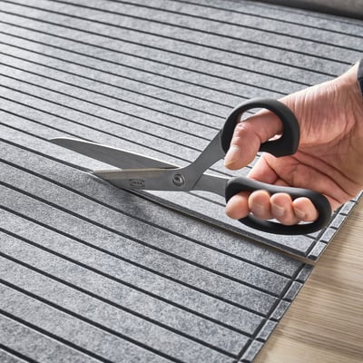 A hand cuts a felt panel with scissors for creating storage doors.