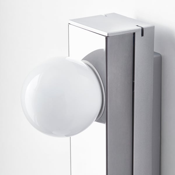 Modern wall-mounted light fixture, sleek design, glossy white shade, smooth metallic finish on base.