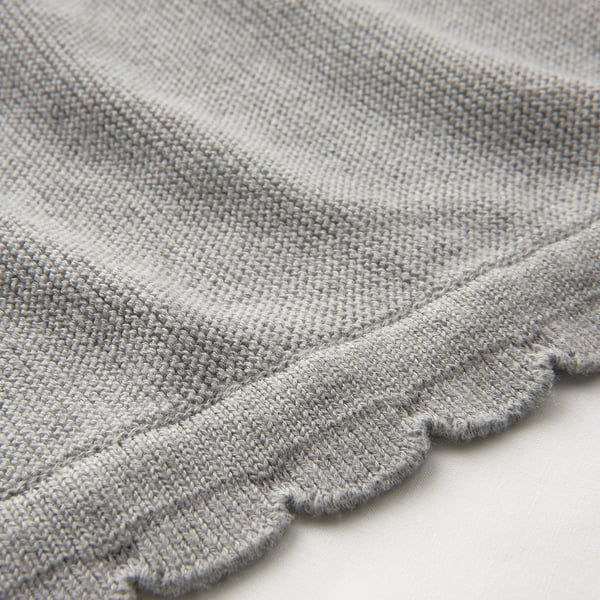Close-up of soft, knitted blanket with scalloped edge, showcasing its texture and quality.