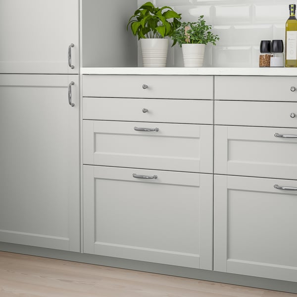 Grey LERHYTTAN kitchen cabinets with birch drawers & handles. Large drawers beside white countertop with green plants.