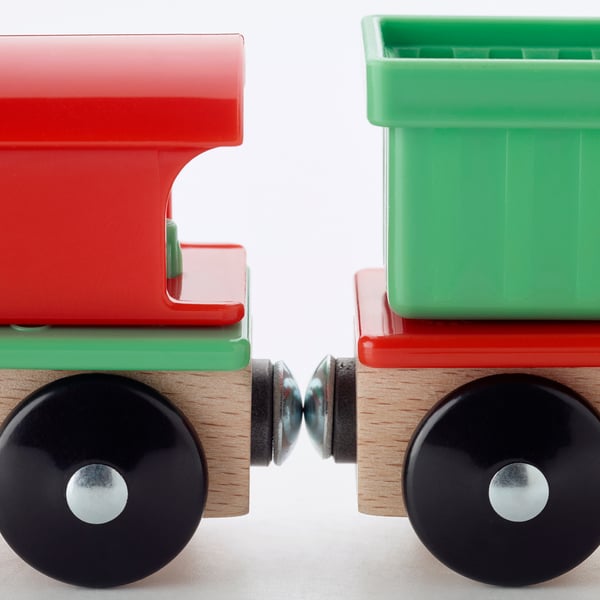 Two vibrant toy train cars, red and green, with sturdy black wheels, connected together.