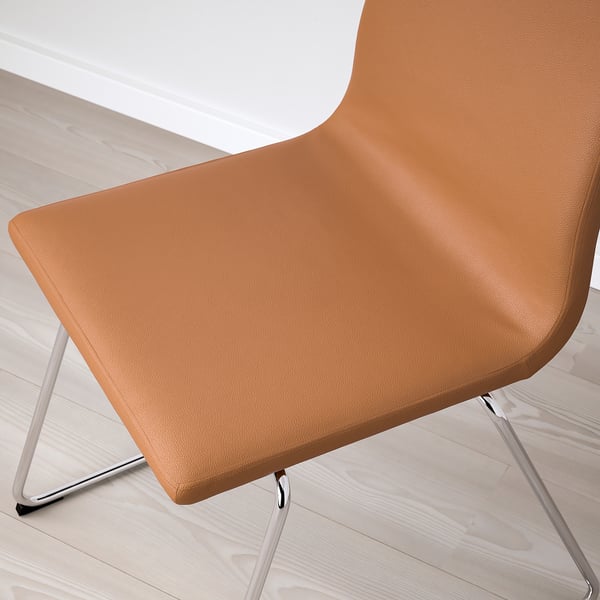 Modern upholstered chair with padded seat and back, featuring high-quality grain leather in brown, supported by a chrome-plated sled base.