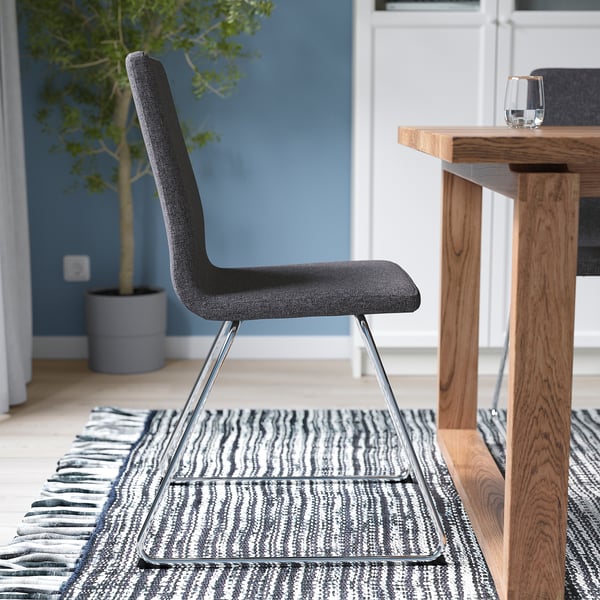 Modern grey chair with chrome base beside table, removable cover for easy washing.