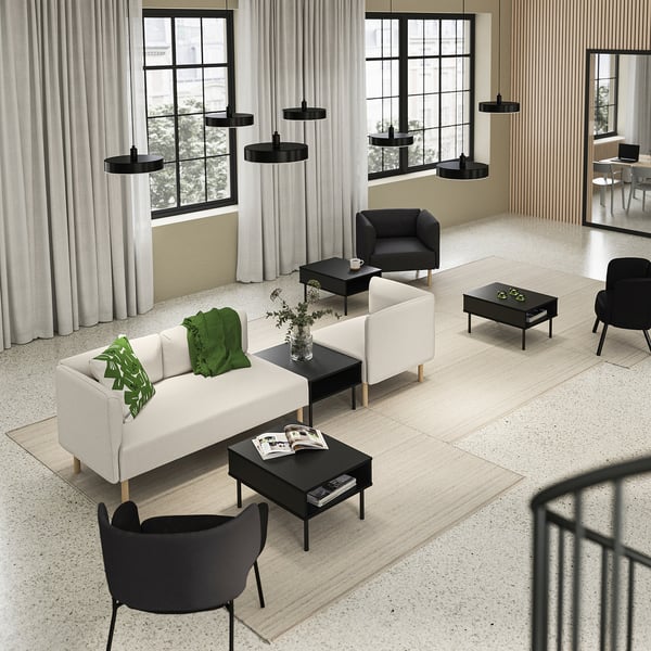 Modern living space with white LILLEHEM sofas, black coffee tables, and black chairs, accented with green throws and decorative plants.