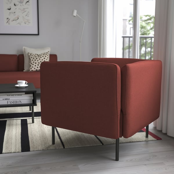 Two red upholstered chairs in living room, with wooden floor, rug, coffee table, and large window.