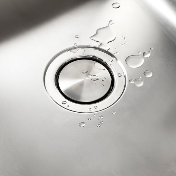 Stainless steel sink lid with magnetic base, scattered water droplets, clean flat surface.