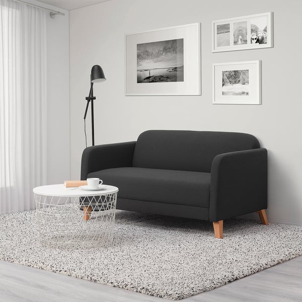 Minimalist living room with LINANÄS dark grey sofa, side table, lamp and rug.