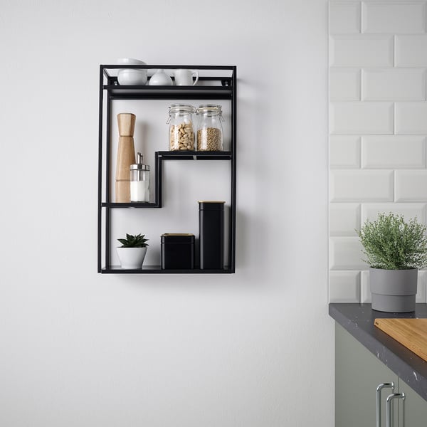Modern black LINDÅSEN wall shelf displays kitchen items, including jars, plant, and wooden grinder. Versatile, stylish, and compact.
